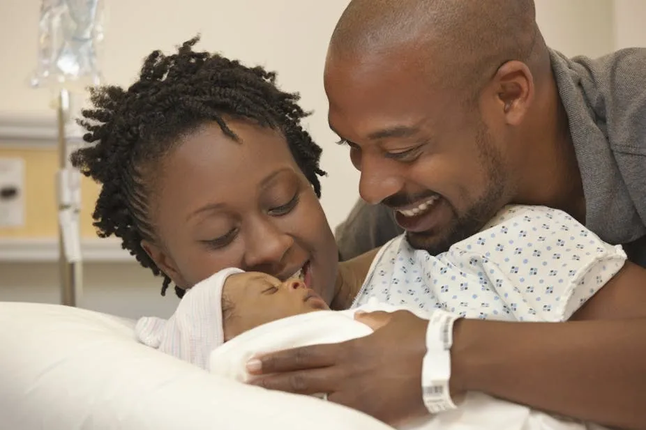 A man supports a woman in a hospital bed, promoting maternal health care and partnership in Rwanda.